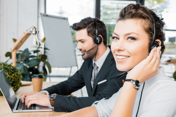 side view of smiling call center operators at workplace in office - Foto, Bild