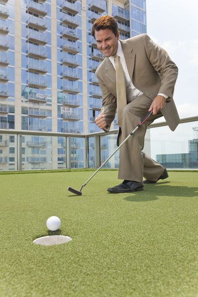 Empresario exitoso jugando golf en la azotea del rascacielos
 - Foto, imagen
