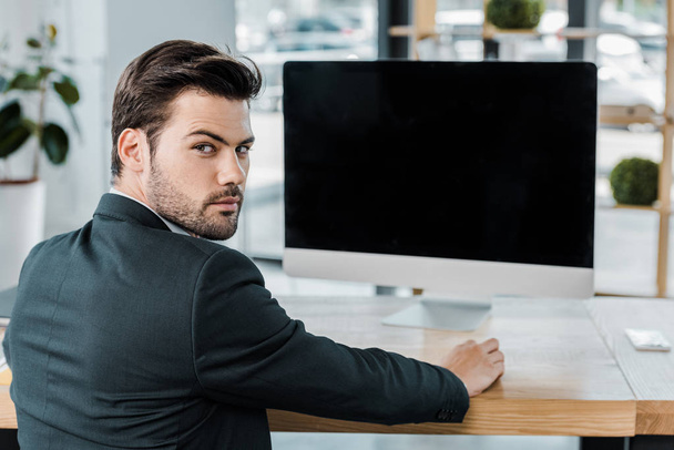 vista posterior del hombre de negocios en el lugar de trabajo con pantalla de computadora con pantalla en blanco en la oficina
 - Foto, imagen
