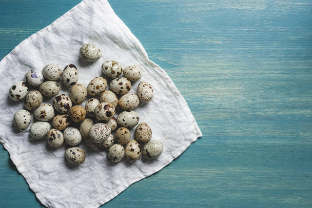 fresh organic quail eggs on white cloth on turquoise wooden table - 写真・画像