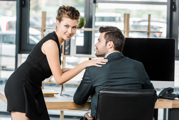 young businesswoman holding colleagues tie while flirting at workplace in office - Valokuva, kuva