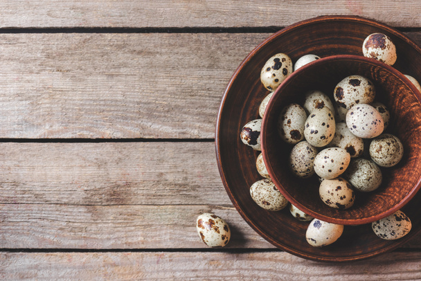 top view of fresh raw organic quail eggs in bowls on wooden table - Foto, Imagem