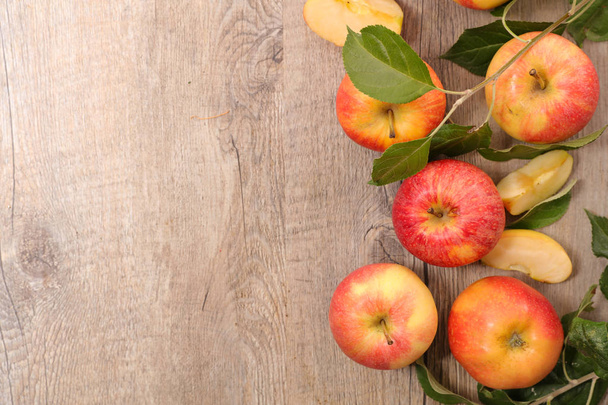 Fresh apples and leaves on wooden background - Foto, afbeelding