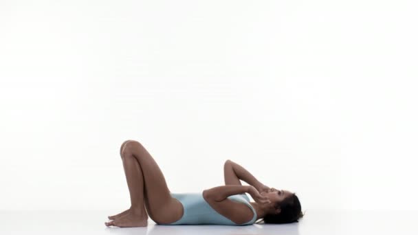 Mujer haciendo ejercicios de estiramiento y gimnasia sobre fondo blanco
 - Imágenes, Vídeo