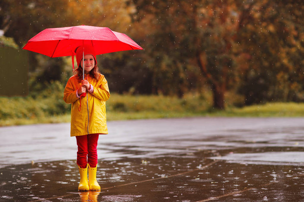 niña feliz con un paraguas y botas de goma saltar en charco en un wal otoño
 - Foto, Imagen
