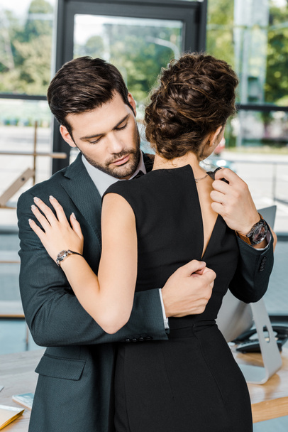 young businessman unzipping dress of seductive businesswoman at workplace in office - Photo, Image