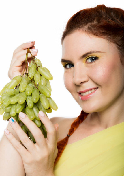 Beautiful redhead woman licks grapes. concept of healthy eating - Foto, imagen