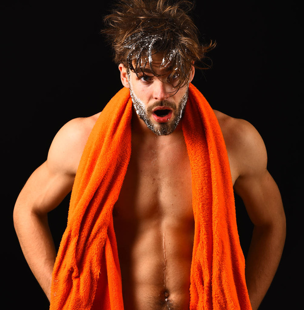 Body care. Macho attractive nude guy black background. Man bearded tousled hair covered with foam or soap suds. Wash off foam with water carefully. Man with orange towel on neck ready to take shower - Photo, image