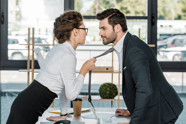 vista lateral del hombre de negocios y la mujer de negocios coqueteando en el lugar de trabajo en la oficina
 - Foto, Imagen
