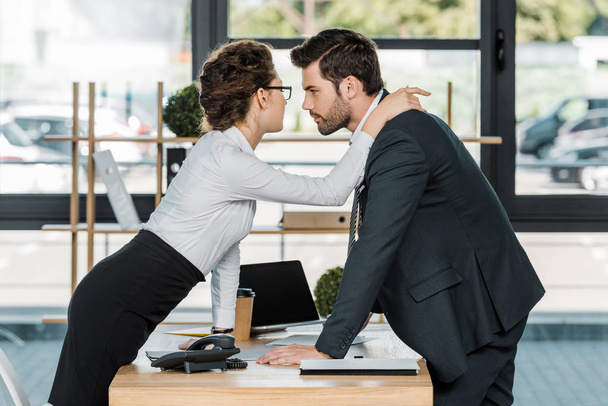vista laterale di uomo d'affari e donna d'affari flirtare sul posto di lavoro in ufficio
 - Foto, immagini