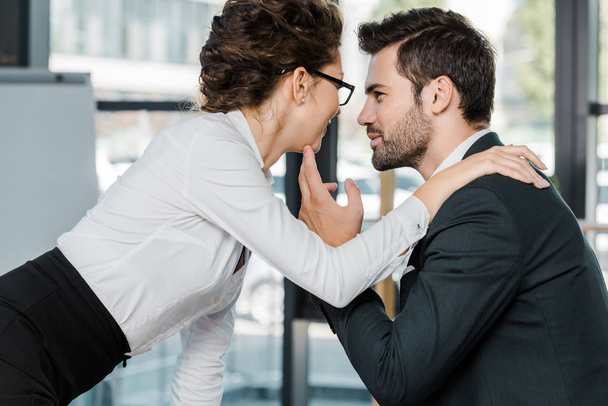 side view of businessman and businesswoman flirtingin office - Foto, afbeelding