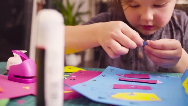 Pieni tyttö liimaamalla värillinen paperi
 - Materiaali, video
