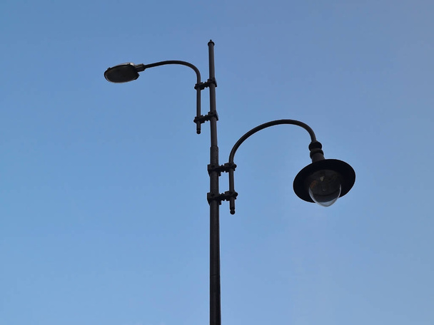 Вулична лампа з двома вогнями на фоні блакитного неба, вид знизу
 - Фото, зображення