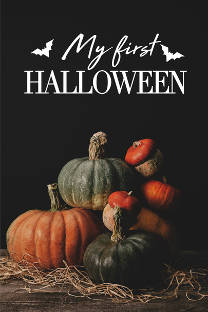 stapel van rijpe pumpkins op tafel met vleermuizen en "mijn eerste halloween" belettering   - Foto, afbeelding