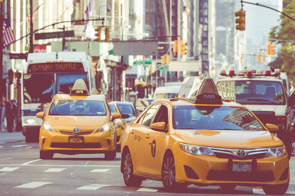 NEW YORK - SEPTEMBER 2, 2018: Yellow cab speeds through Times Square the busy tourist intersection of neon art and commerce and is an iconic street of New York City, USA. - Zdjęcie, obraz