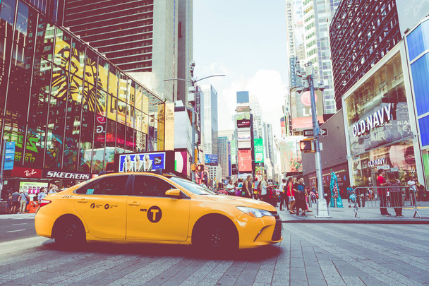 NEW YORK - SEPTEMBER 2, 2018: Yellow cab speeds through Times Square the busy tourist intersection of neon art and commerce and is an iconic street of New York City, USA. - Photo, image