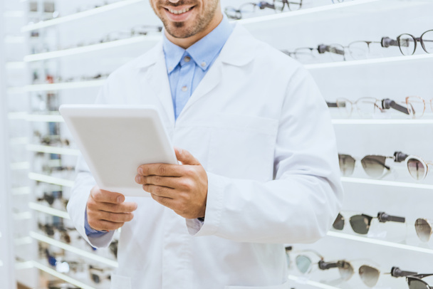 обрізаний вид окуліста в білому пальто з використанням цифрового планшета в оптиці
 - Фото, зображення
