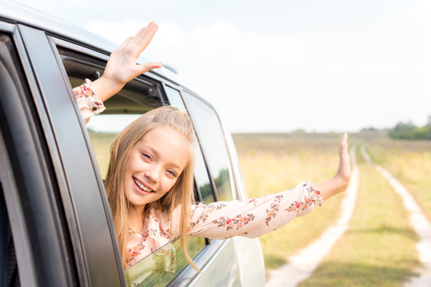 celebrating little child looking out of car window while riding by field - Photo, image