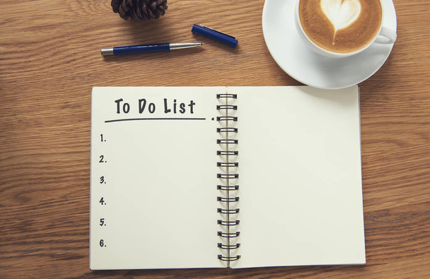 Coffee cup and notebook with to do list on rustic desk from above, planner and checklist concept. - Photo, image