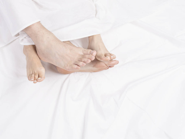 Love lying in bed, embracing on white sheets, close up legs. - Fotoğraf, Görsel
