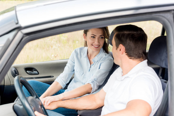 happy adult couple holding hands while sitting in car - Photo, image