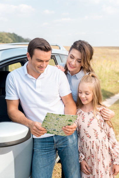 schöne Familie schaut gemeinsam auf die Landkarte während der Autofahrt im Feld - Foto, Bild