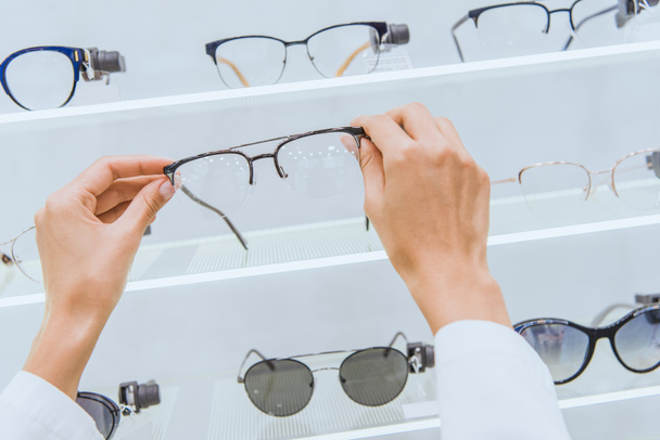 przycięte widzenia lekarz biorąc okulary z półki w sklepie okulistyczne - Zdjęcie, obraz