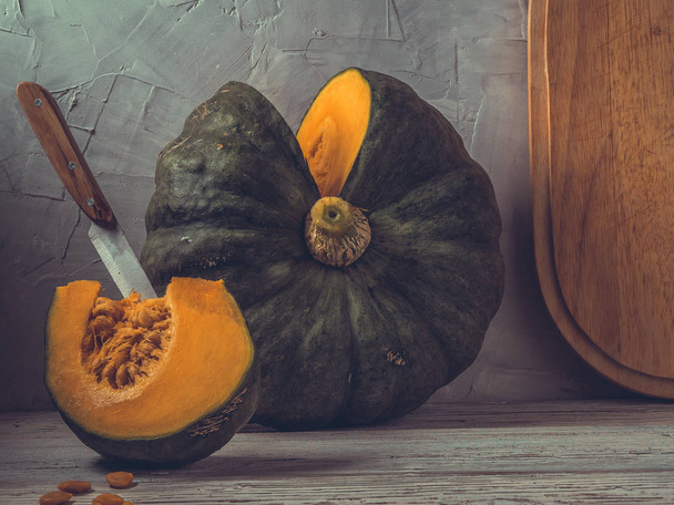Cut pumpkin on a table on the background of a concrete wall. Toned photo. - Фото, зображення