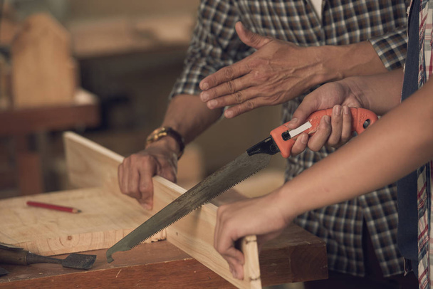 carpenters sawing wooden plank with saw, cropped image - Photo, Image