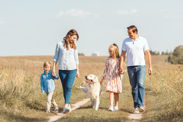 幸せな若い家族はレトリーバー犬フィールドに一緒に時間を過ごすと - 写真・画像