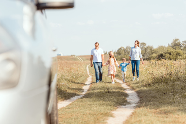 bela jovem família de mãos dadas e andando de carro por campo
 - Foto, Imagem