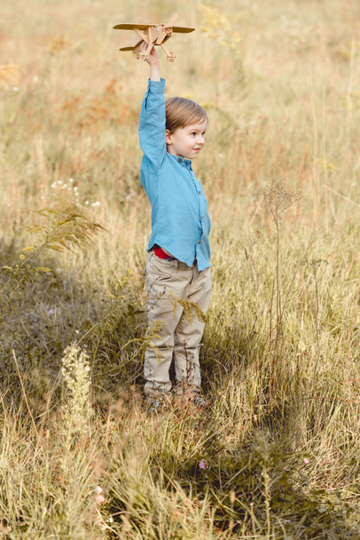 cute little kid in field playing with toy airplane in field - Photo, Image