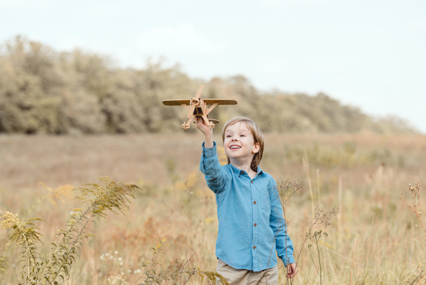 bambino felice in campo che gioca con aeroplano giocattolo in campo
 - Foto, immagini