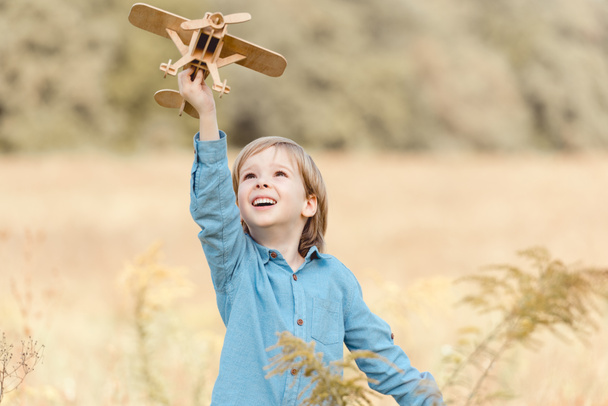 美しいフィールドでおもちゃの飛行機で遊んでフィールドで幸せな子供 - 写真・画像