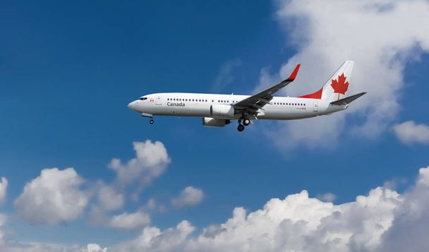 Samolot pasażerski niestandardowe flaga Kanady na ogonie. Błękitne niebo pochmurne, w tle - Zdjęcie, obraz
