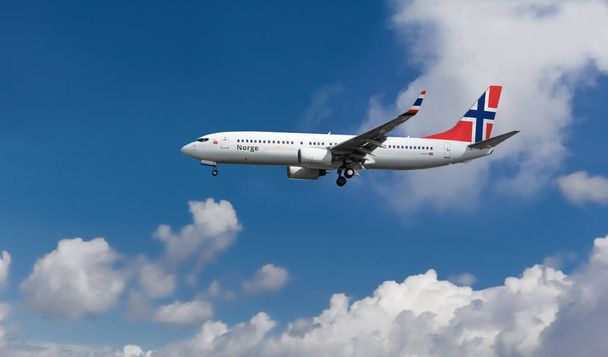 Samolot pasażerski niestandardową flagą norweski na ogonie. Błękitne niebo pochmurne, w tle - Zdjęcie, obraz
