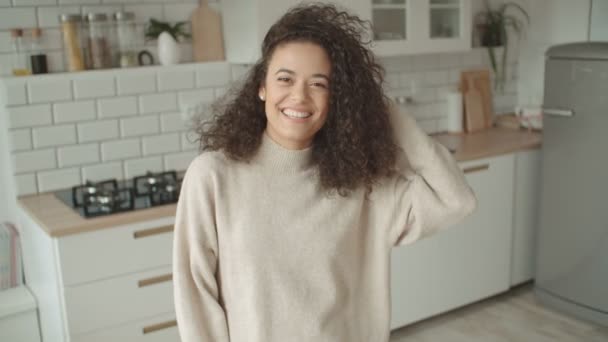 Portrait of a beautiful young woman smiling at the camera in a kitchen. - Video