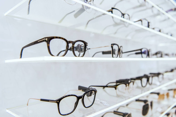 selective focus of white shelves with trendy glasses in ophthalmic shop - Foto, Bild
