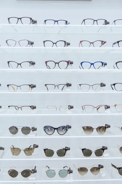polcok, az elegáns szemüveget és divatos napszemüveg szemészeti üzletben - Fotó, kép