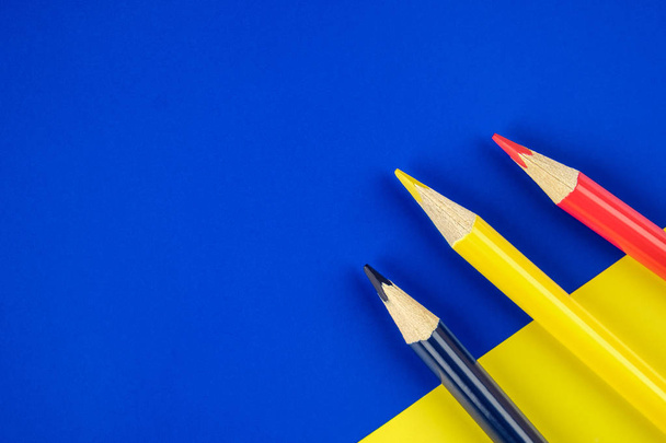 Colored pencils blue, yellow and red on color papers geometry flat composition background - Photo, Image