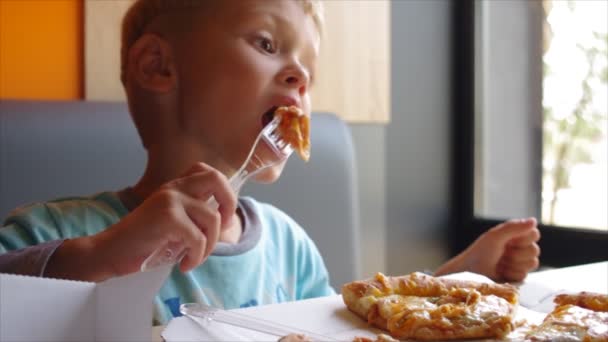 kleine schattige jongen eten pizza met eetlust - Video