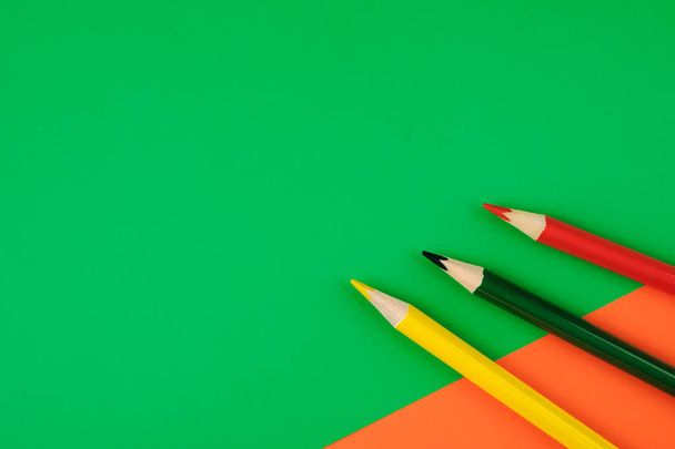 Colored pencils green, yellow and red on color papers geometry flat composition background - Foto, immagini