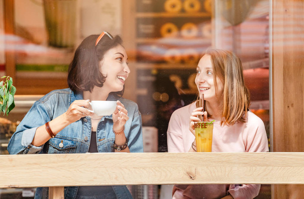 Bir kafede yemek, kahve içme ve konuşmak iki mutlu kız. Dostluk ve yaşam tarzı kavramı - Fotoğraf, Görsel