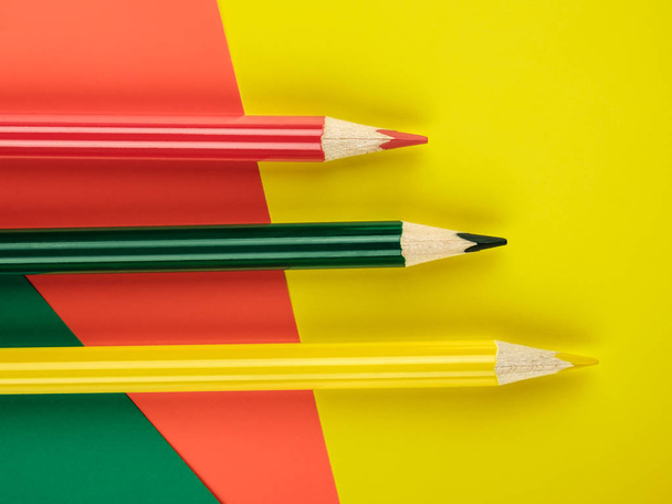 Colored pencils green, yellow and red on color papers geometry flat composition background - Foto, imagen