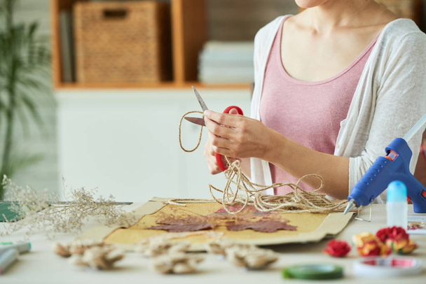 Cropped image of woman making picture with dry leaves and string - Foto, imagen