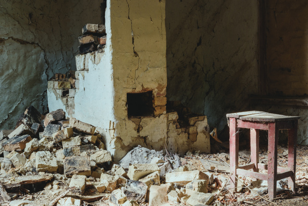 abandoned building with broken brick wall and wooden chair with dust - Photo, Image