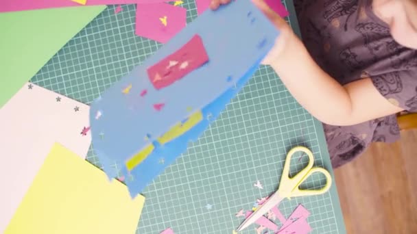 Mała dziewczynka cięcia kolorowego papieru nożyczkami - Materiał filmowy, wideo