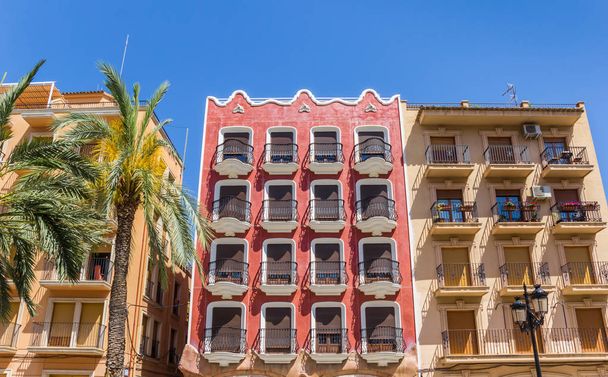Colorido edificio de apartamentos rojo en la plaza principal de Ayora, España
 - Foto, imagen