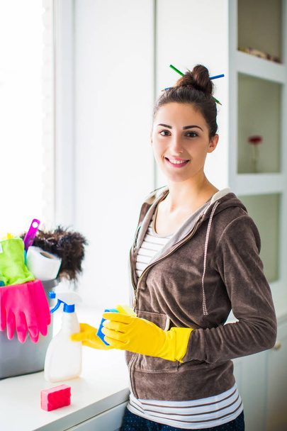 Portrait of the young smiling woman who standing near window and things for cleaning at home - 写真・画像
