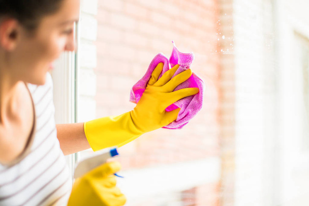 Zbliżenie młoda kobieta szczęśliwa w rękawice mycie okien w domu - Zdjęcie, obraz